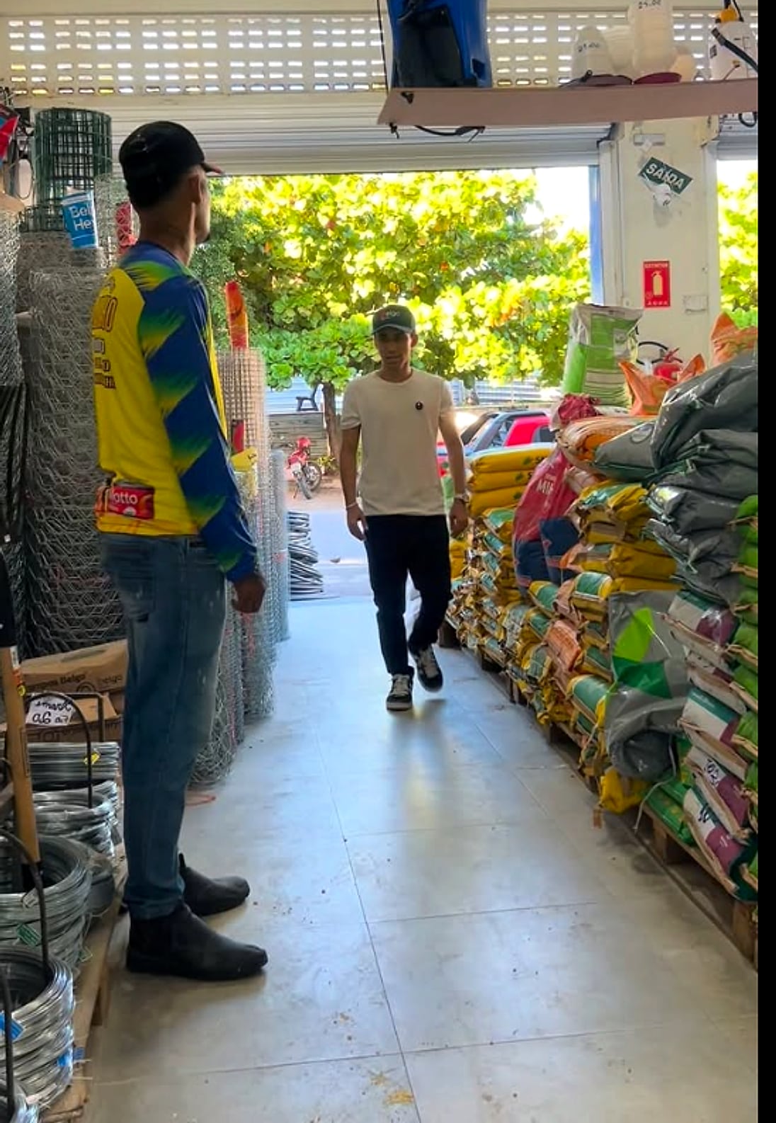 Corredor da loja com rolos de arame e sacos de ração